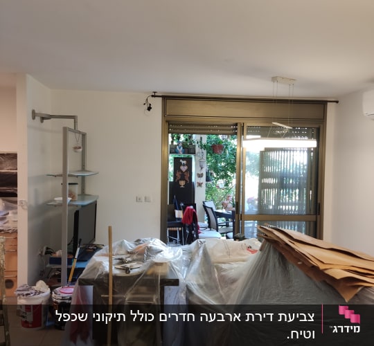 חדר עם רהיטים מכוסים בניילון, דלי צבע ומטאטא